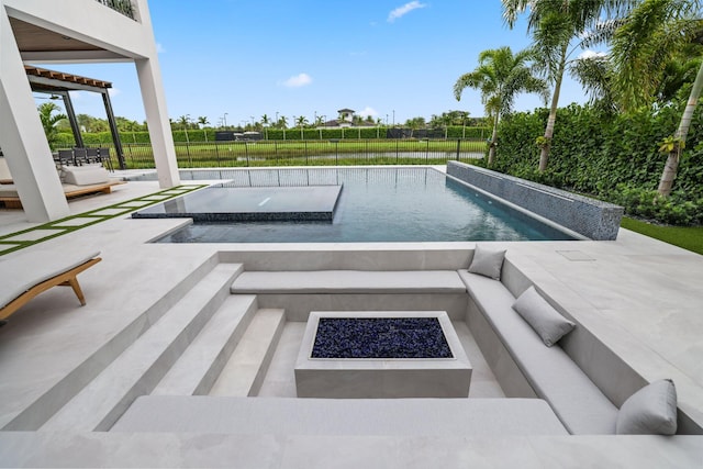 view of swimming pool with a patio, a hot tub, and an outdoor living space with a fire pit