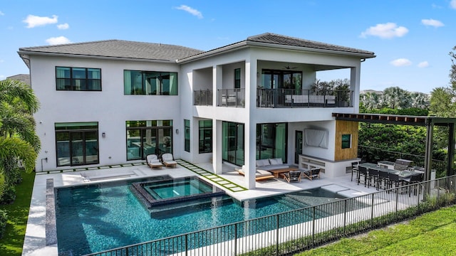 rear view of property featuring a balcony, a swimming pool with hot tub, an outdoor hangout area, and a patio area