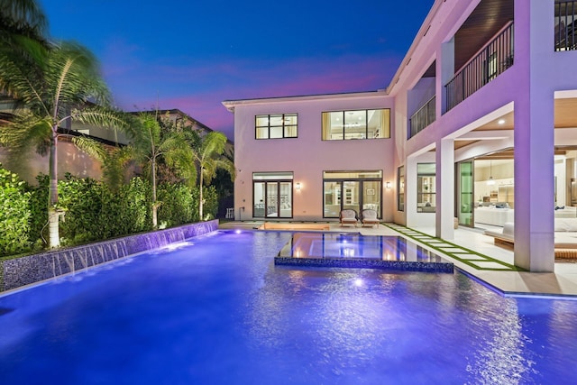 pool at dusk featuring a patio area and pool water feature