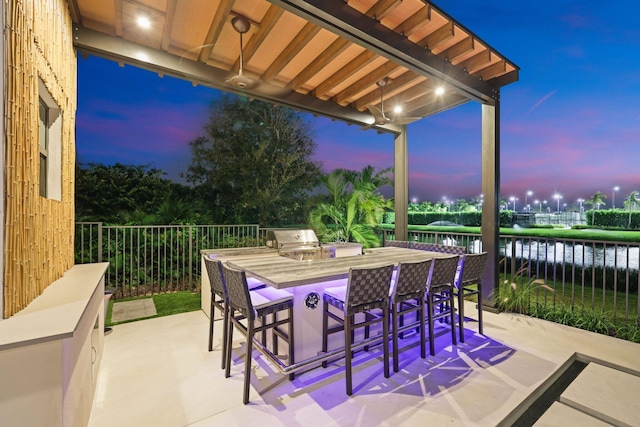 patio terrace at dusk featuring a water view and grilling area