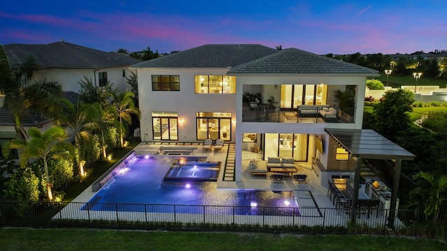 back house at dusk featuring a patio, a balcony, pool water feature, outdoor lounge area, and a swimming pool with hot tub