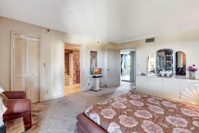 carpeted bedroom featuring a closet, a textured ceiling, and ensuite bathroom