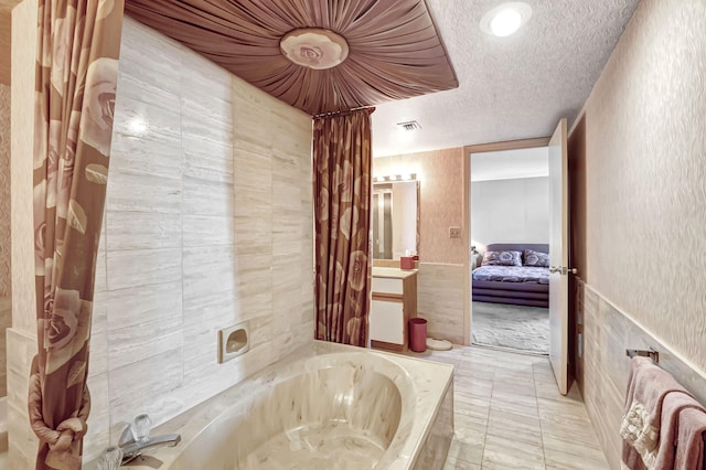 bathroom featuring a bathtub, a textured ceiling, and tile walls