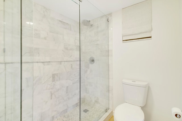 bathroom with a shower with door and toilet