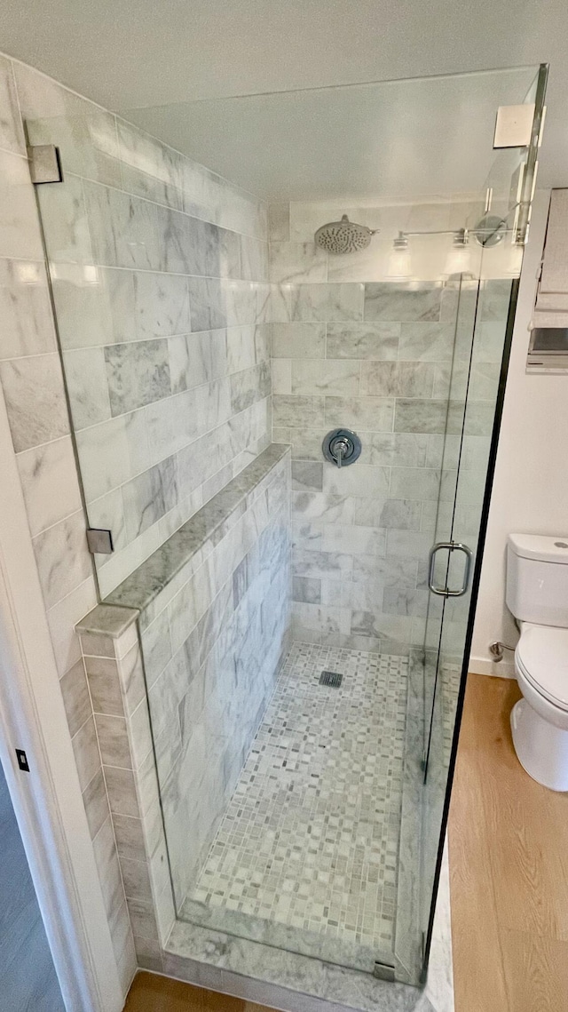 bathroom featuring toilet, hardwood / wood-style flooring, and a shower with shower door