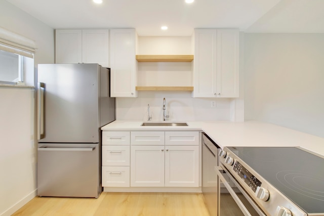 kitchen with light hardwood / wood-style flooring, stainless steel appliances, sink, and white cabinets