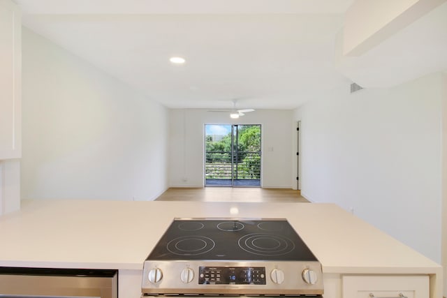 kitchen with white cabinets, ceiling fan, and stainless steel stove