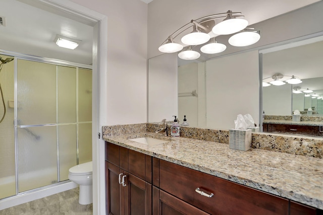 bathroom with a shower with door, vanity, and toilet