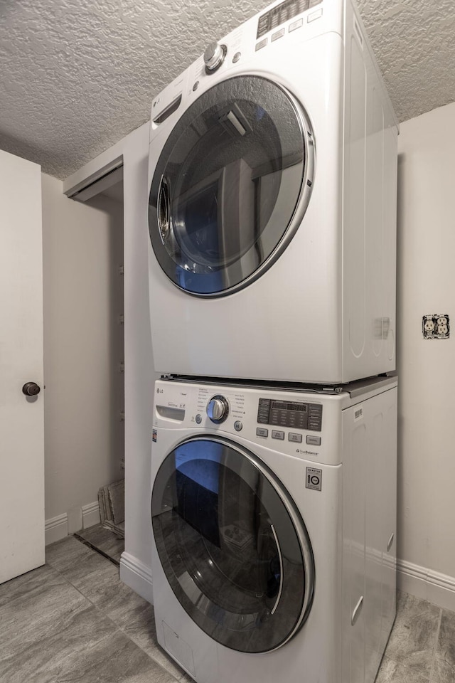 laundry room featuring a textured ceiling and stacked washer / drying machine