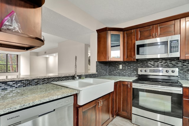 kitchen with sink, appliances with stainless steel finishes, decorative backsplash, and light stone counters