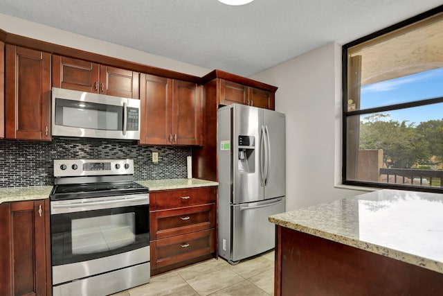 kitchen featuring decorative backsplash, a textured ceiling, light tile patterned floors, light stone countertops, and appliances with stainless steel finishes