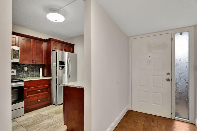 kitchen featuring light hardwood / wood-style flooring, light stone countertops, decorative backsplash, and stainless steel appliances