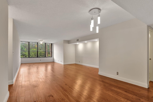 unfurnished living room with hardwood / wood-style floors, ceiling fan, and a textured ceiling