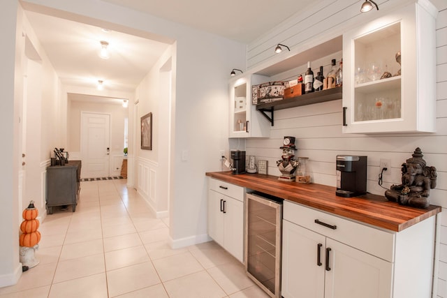 bar with decorative backsplash, beverage cooler, light tile patterned floors, white cabinetry, and butcher block counters