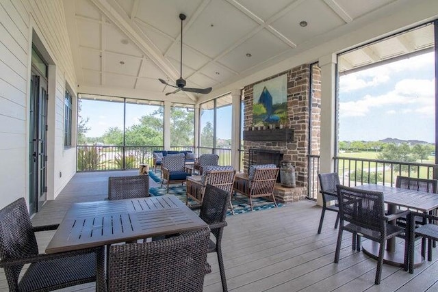 sunroom / solarium featuring ceiling fan, a healthy amount of sunlight, and an outdoor stone fireplace