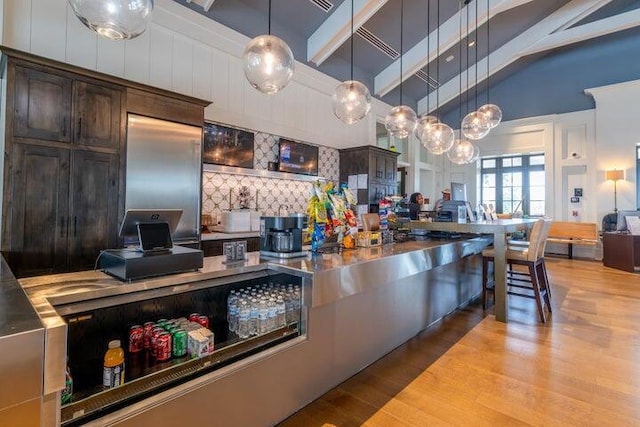 kitchen with light hardwood / wood-style floors, tasteful backsplash, dark brown cabinets, and decorative light fixtures