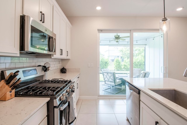 kitchen featuring stainless steel appliances, sink, white cabinets, light stone counters, and ceiling fan