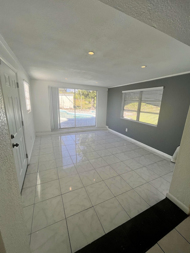 unfurnished room featuring a textured ceiling and light tile patterned floors