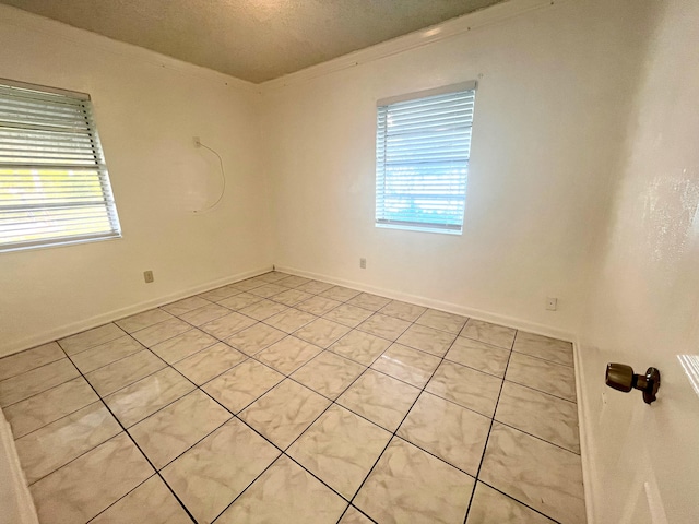 tiled empty room with a healthy amount of sunlight, a textured ceiling, and crown molding