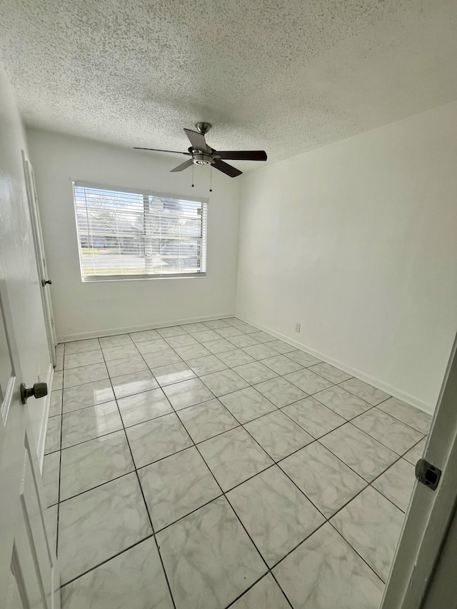 tiled empty room with ceiling fan and a textured ceiling