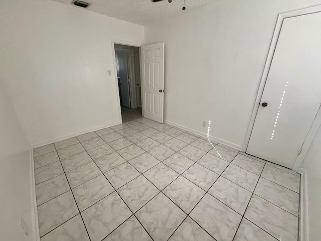 unfurnished room featuring a textured ceiling, light tile patterned floors, and ceiling fan