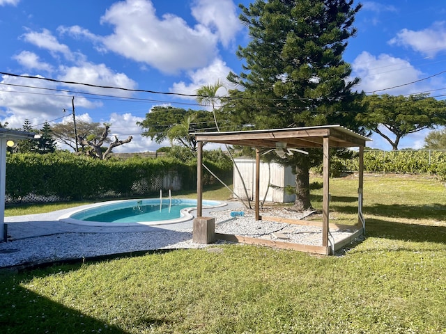 view of pool featuring a shed and a lawn