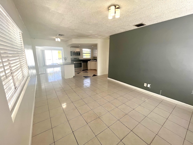 unfurnished living room with a textured ceiling and light tile patterned floors