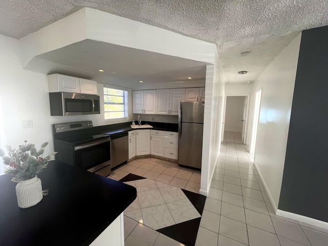 kitchen featuring stainless steel appliances, light tile patterned flooring, sink, a textured ceiling, and white cabinets