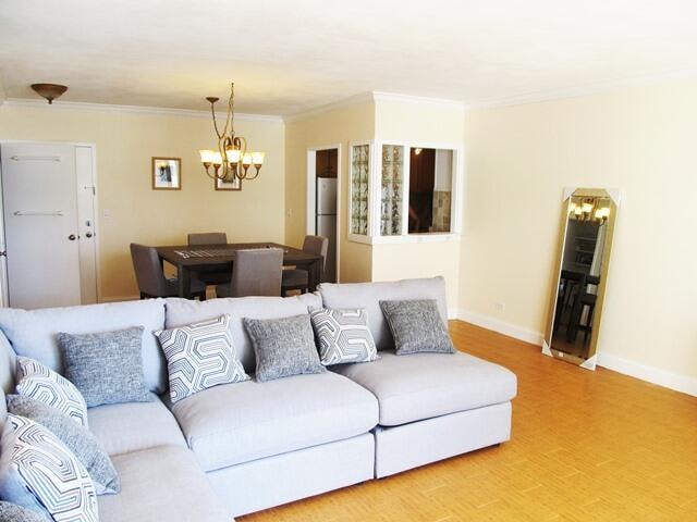 living room with crown molding and a chandelier