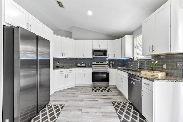 kitchen featuring appliances with stainless steel finishes, tasteful backsplash, white cabinetry, and dark stone countertops