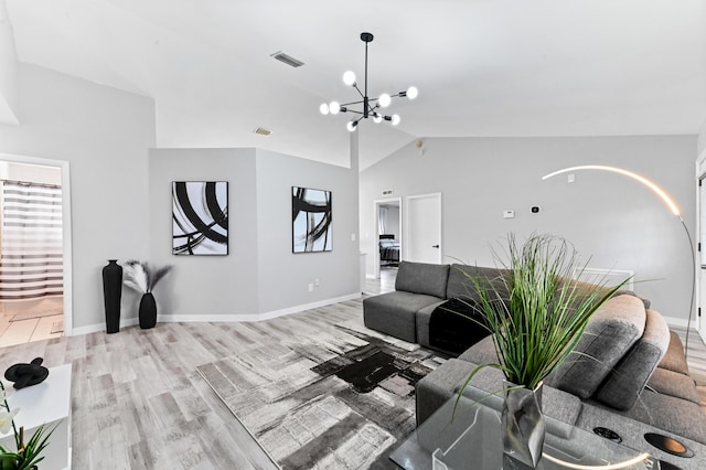 living room with hardwood / wood-style floors, lofted ceiling, and a chandelier