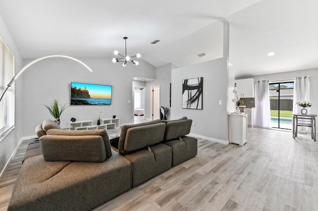 living room with a chandelier, light hardwood / wood-style flooring, and lofted ceiling