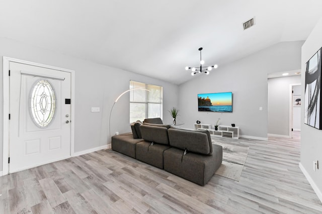 living room with light hardwood / wood-style floors, an inviting chandelier, and vaulted ceiling