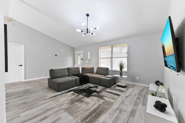 living room with light hardwood / wood-style floors, lofted ceiling, and an inviting chandelier