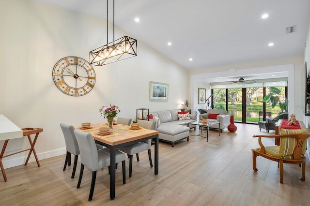 dining space with light hardwood / wood-style floors, high vaulted ceiling, and ceiling fan with notable chandelier