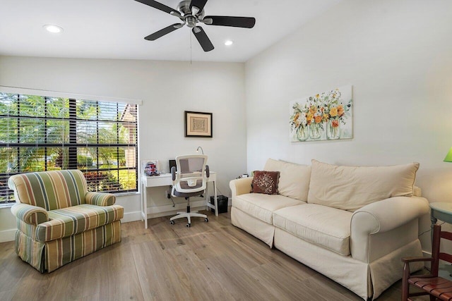 living room with light hardwood / wood-style flooring, built in desk, lofted ceiling, and ceiling fan