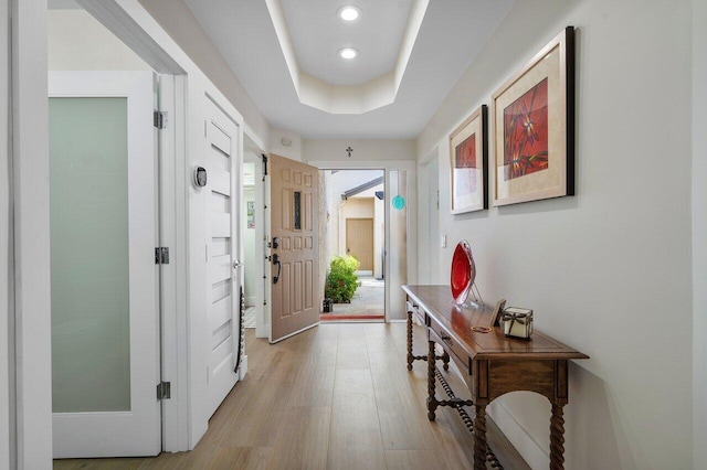 doorway featuring a tray ceiling and light hardwood / wood-style floors