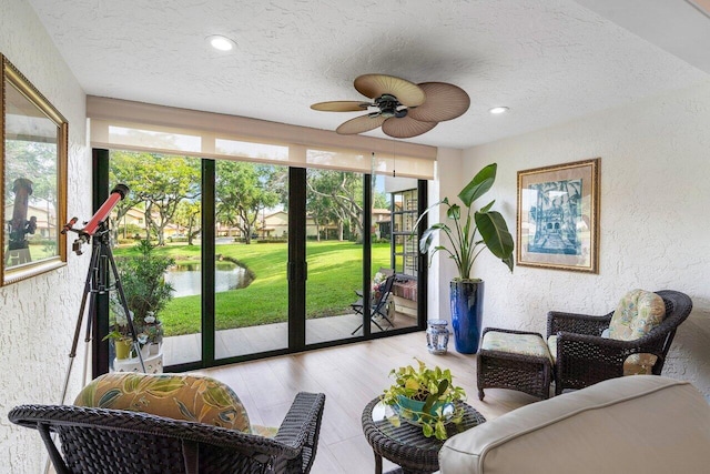 sunroom featuring a water view, ceiling fan, and plenty of natural light