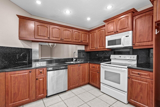 kitchen with tasteful backsplash, white appliances, a textured ceiling, and light tile patterned floors