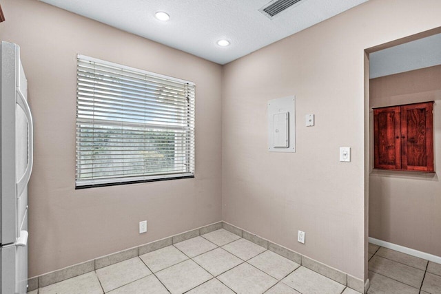 tiled empty room featuring a textured ceiling