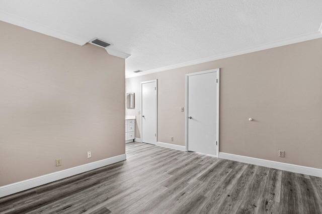 spare room featuring hardwood / wood-style flooring, ornamental molding, and a textured ceiling