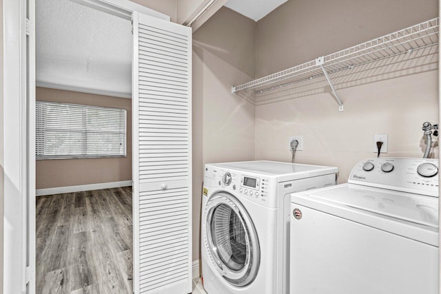 clothes washing area with separate washer and dryer and hardwood / wood-style floors