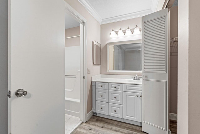 bathroom with crown molding, hardwood / wood-style floors, vanity, and shower / bathtub combination