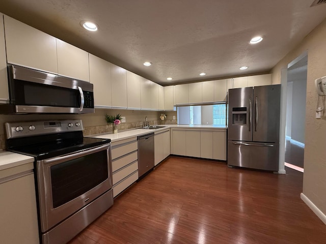 kitchen with white cabinets, dark hardwood / wood-style floors, sink, and stainless steel appliances