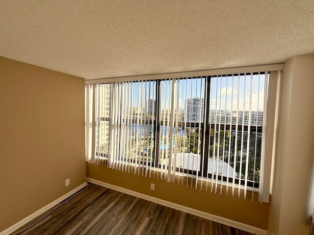 empty room featuring a textured ceiling and dark hardwood / wood-style floors