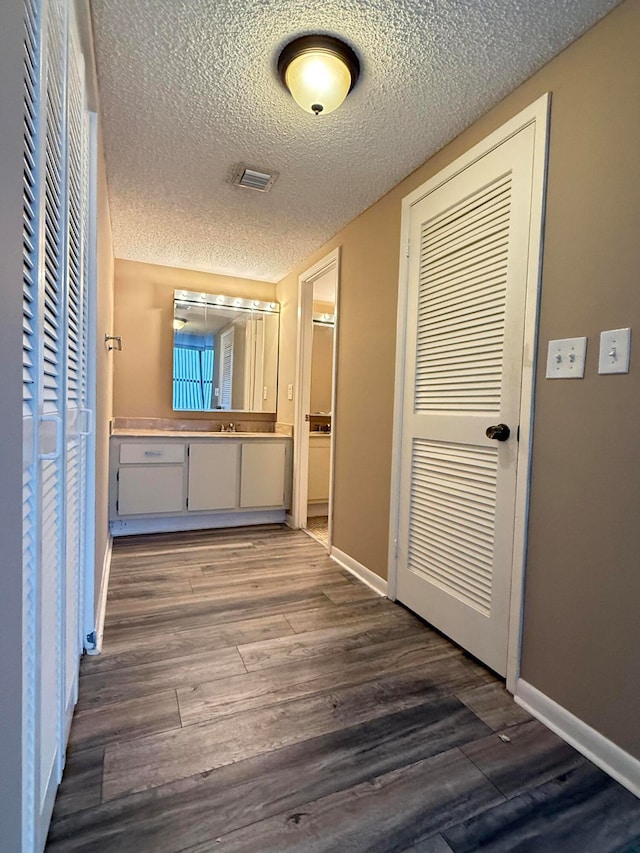 corridor featuring a textured ceiling and hardwood / wood-style flooring