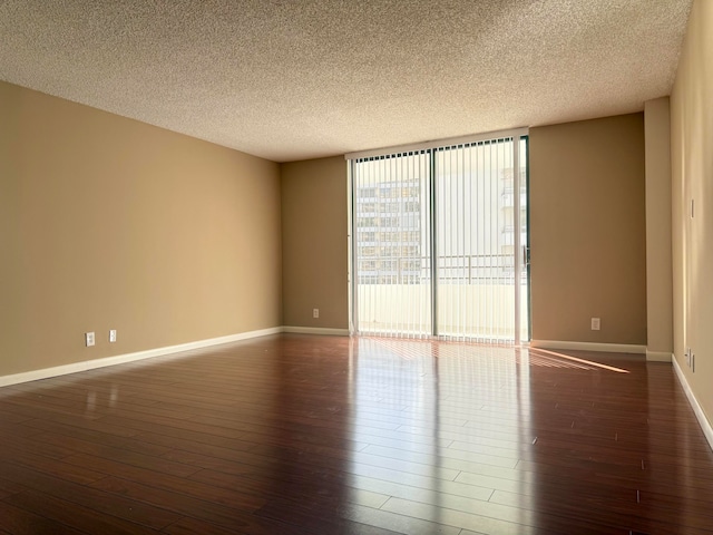 spare room with a textured ceiling, floor to ceiling windows, and dark hardwood / wood-style floors