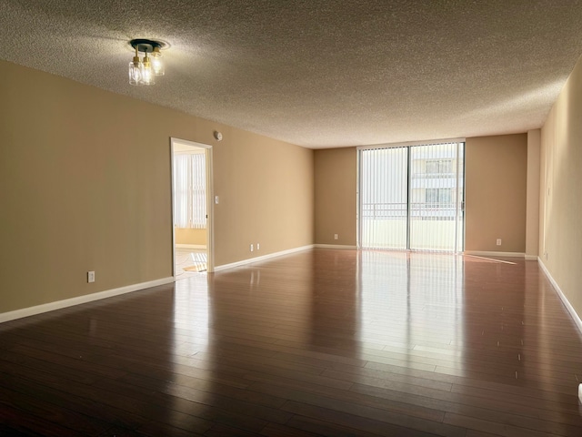 empty room featuring dark hardwood / wood-style floors, a textured ceiling, and a wealth of natural light