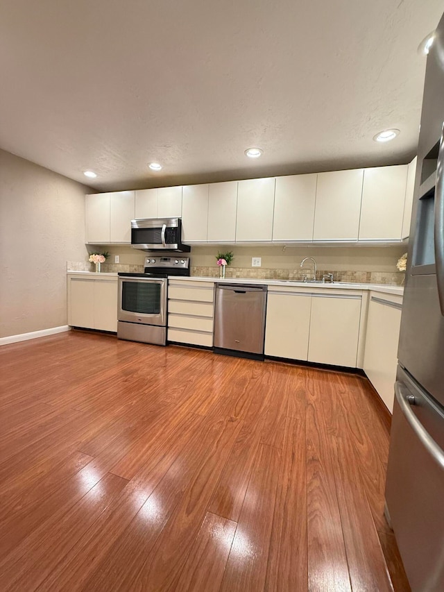 kitchen with sink, white cabinets, stainless steel appliances, and light wood-type flooring