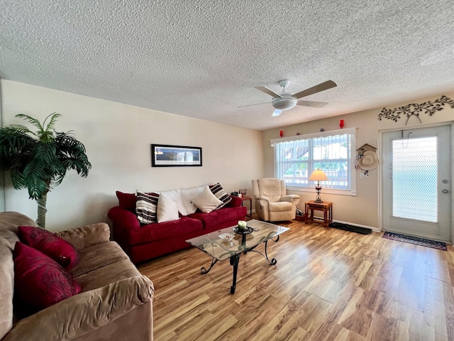 living room featuring a textured ceiling, light wood-type flooring, and ceiling fan